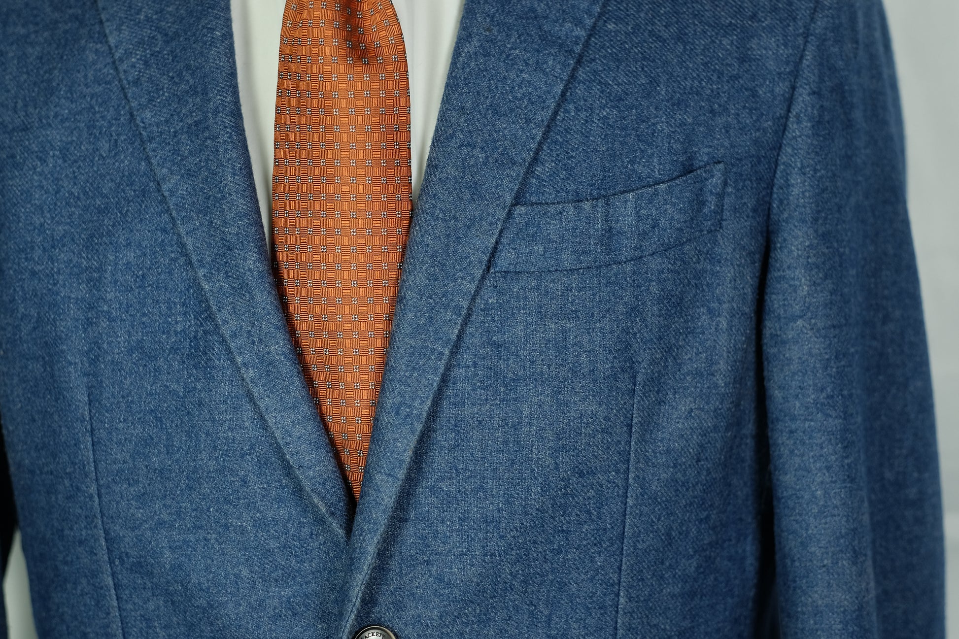 Blue blazer with a red patterned tie on a gray background