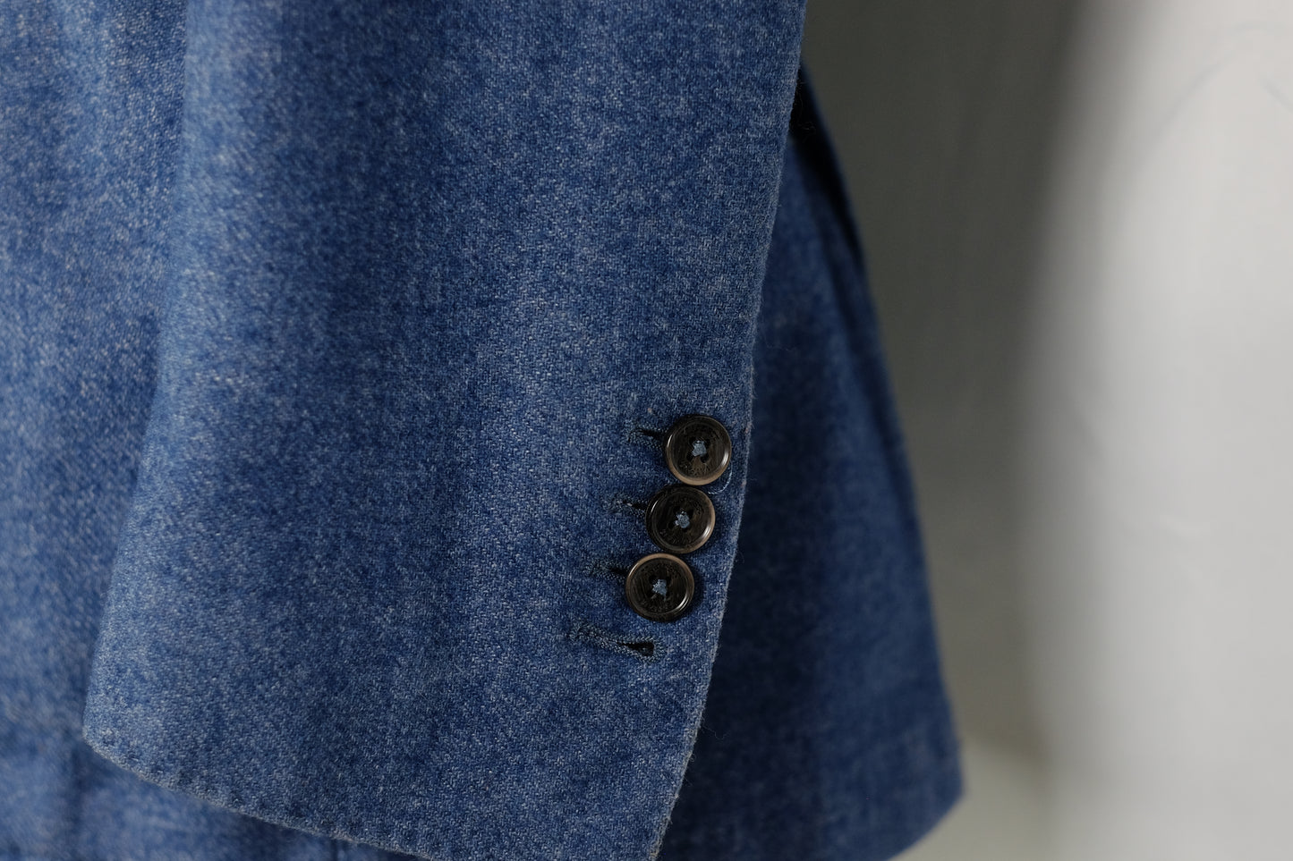 Close-up of a blue textured fabric with buttons on a plain background