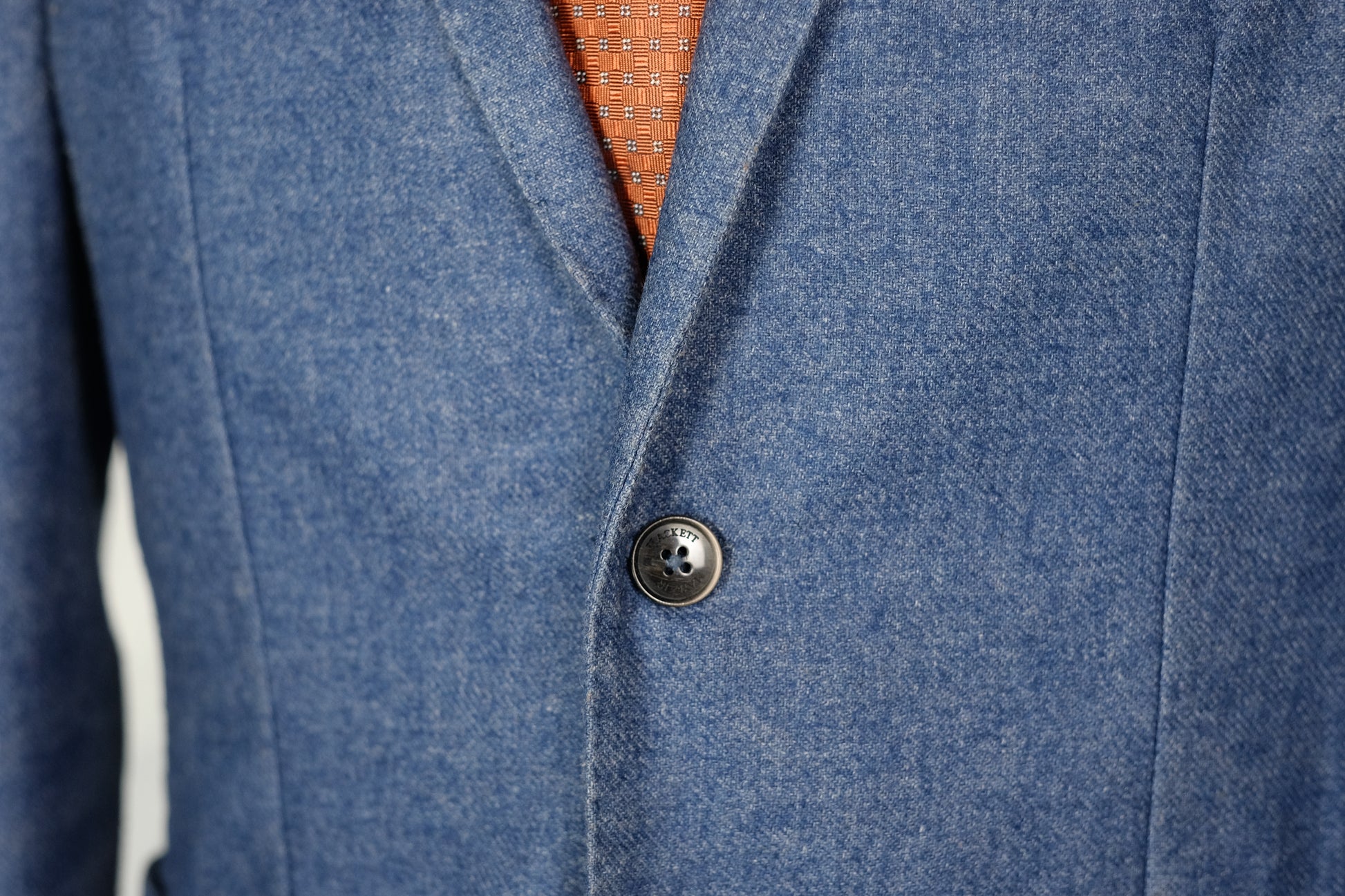 Close-up of a blue coat with a button, showing texture and color details.