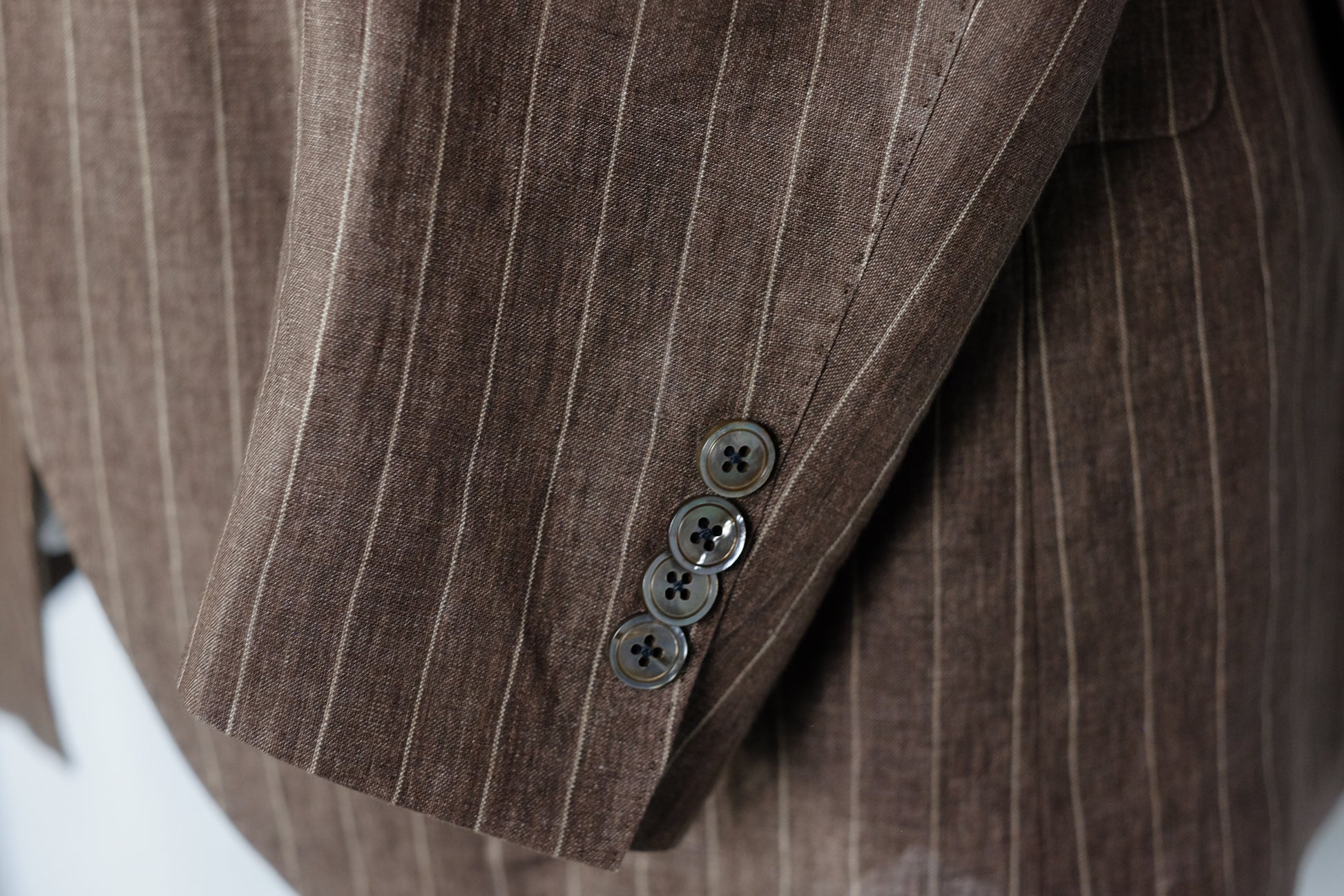 Close-up of a brown pinstripe suit jacket with buttons.